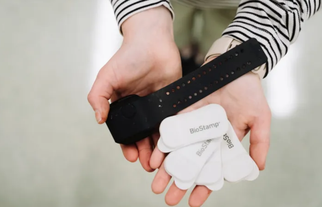 A pair of hands holding an Empatica E4 wrist-worn device and several BioStamp flexible adhesive sensors used across Chapter 1 and Chapter 2.