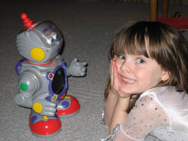 Bryn as a child looking up at a small toy robot.